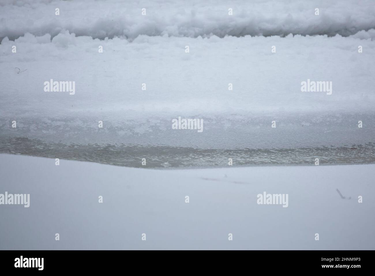 Partially frozen water flowing in ruts in the snow and ice Stock Photo
