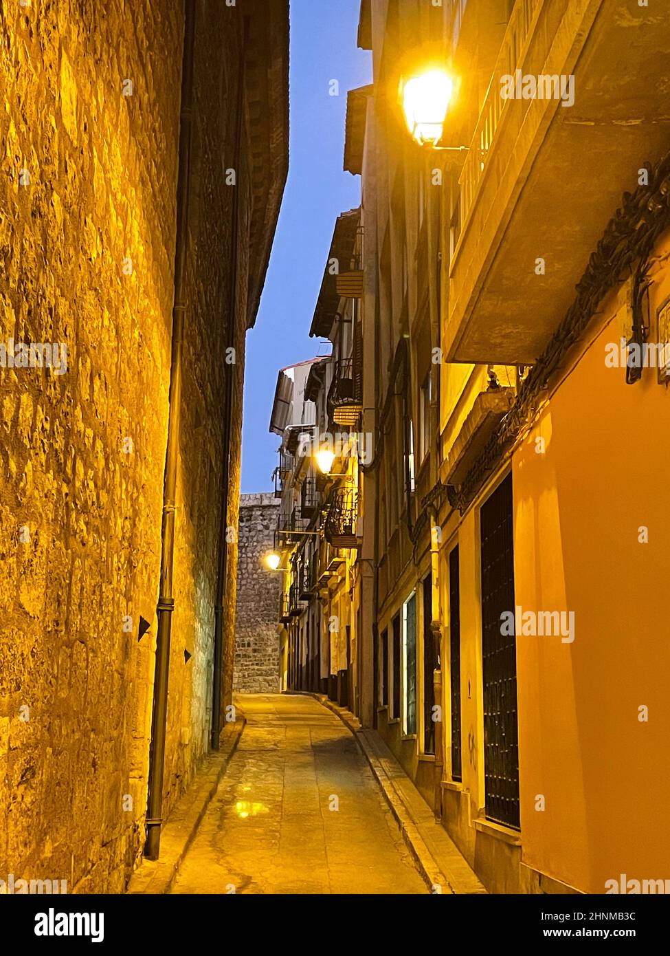 Narrow alley in a Spanish old town in the dark, the street lights are on Stock Photo