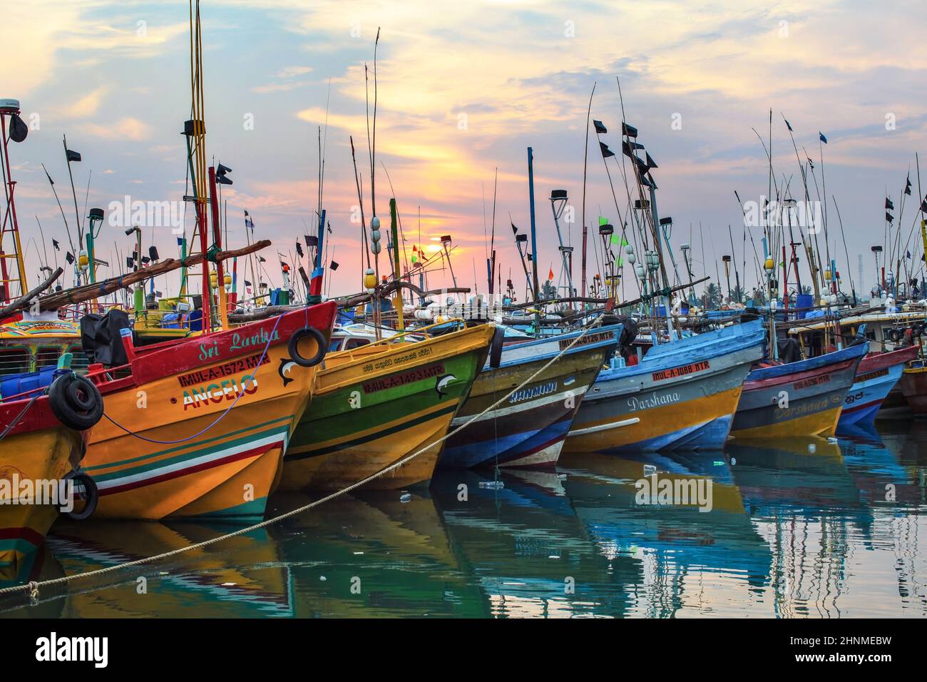Mirissa, Sri Lanka - April 14, 2017: Colorful boats in Mirissa port with morning sun rising in the background. Stock Photo