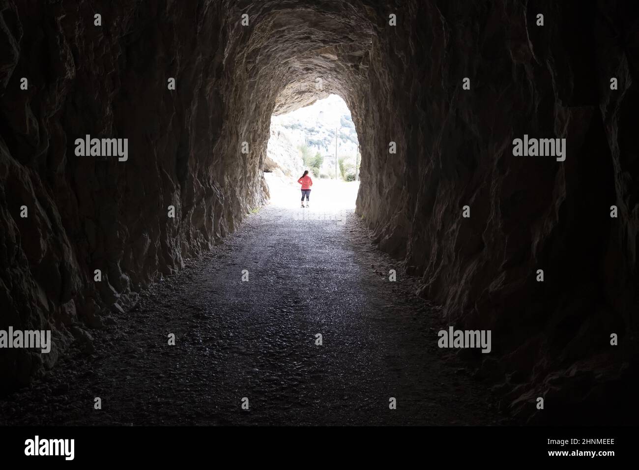 Detail of young woman walking into a dark and deep tunnel Stock Photo