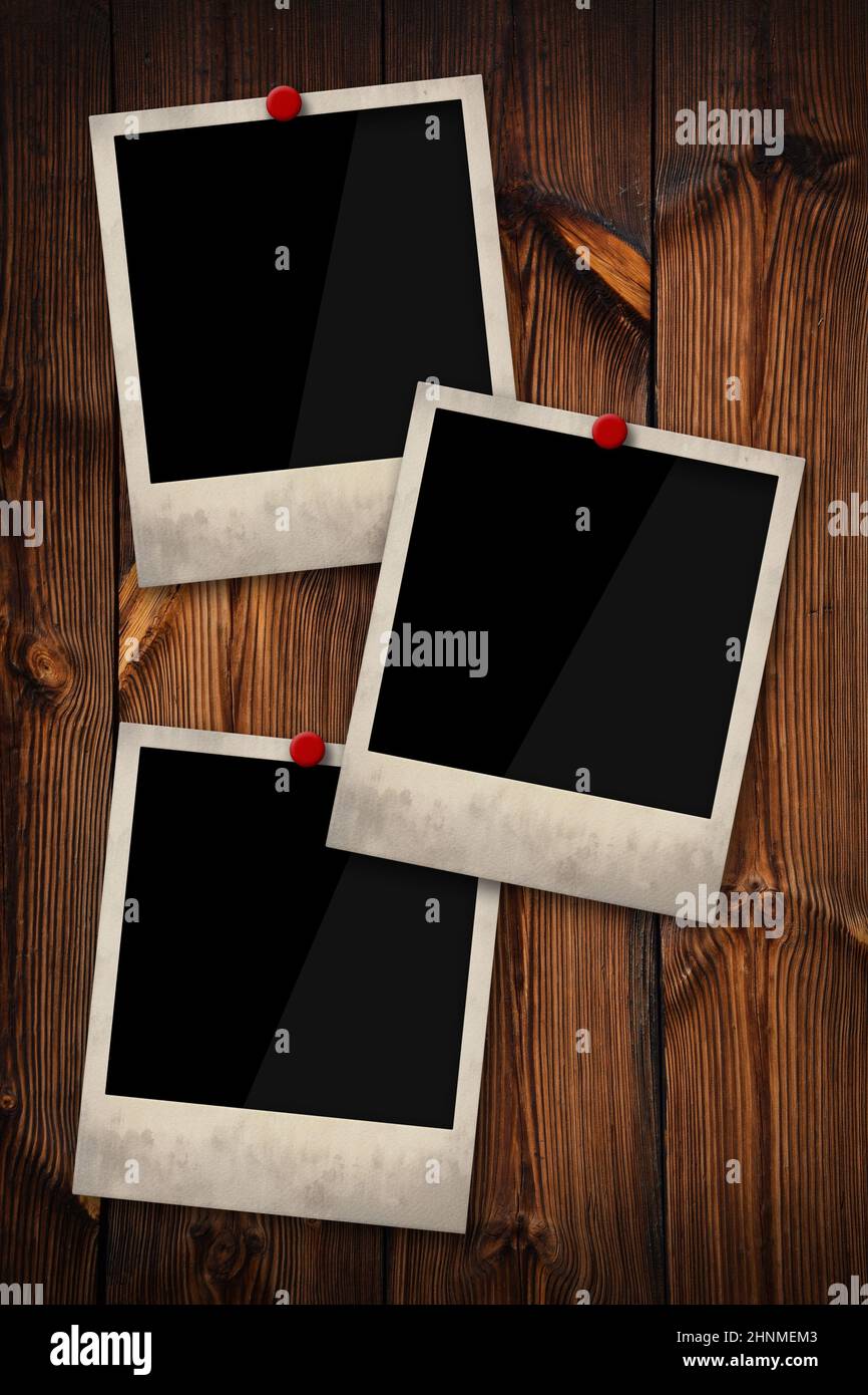 Close up three empty Polaroid instant photo frames pinned on old grunge brown wooden wall background, low angle, side view Stock Photo
