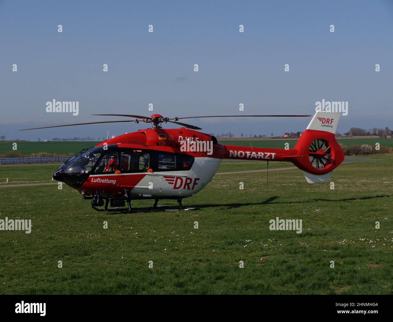 Rescue helicopter D-HILF from Germany on the meadow under a blue sky Stock Photo