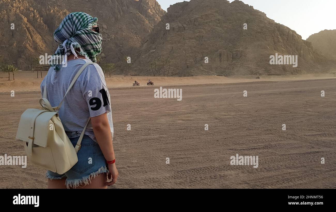 Rear view Portrait of a lonely woman watching a beautiful sunset in the mountains in Egypt. Young girl in the desert. Caucasian woman in off-road desert safari, western desert. Stock Photo