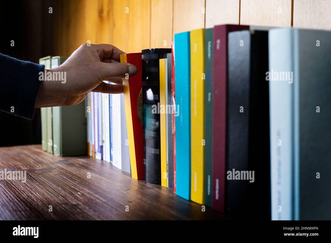 a man takes a book from the bookcase Stock Photo