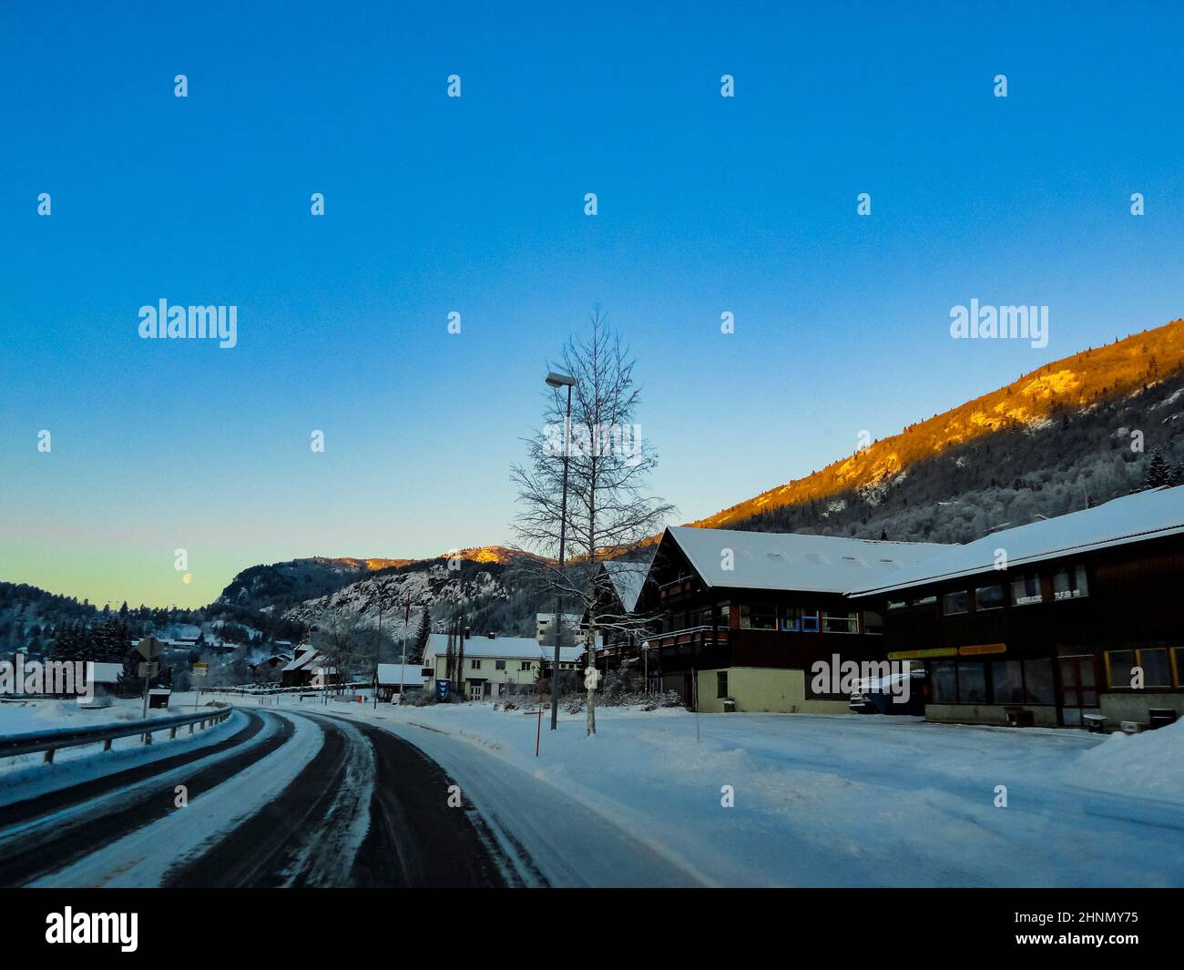 Driving at sunrise through mountains and village in Norway. Stock Photo