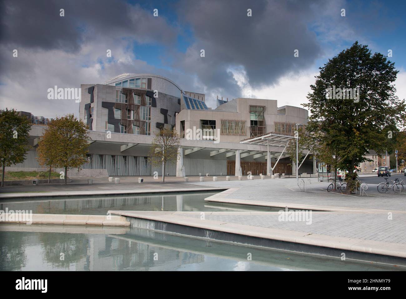 Reflecting pools in front of the Scottish Parliament building in Edinburgh with blue sky and storm clouds looming Stock Photo