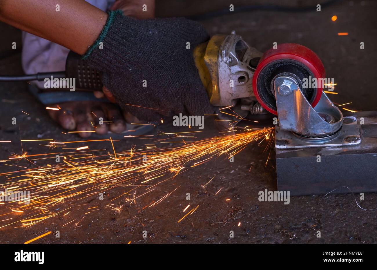 Industrial worker using angle grinder cutting metal. Worker working with angle grinder and has orange sparks. Tool for cut and grinding steel. Safety in industrial workplace. Metal factory industry. Stock Photo