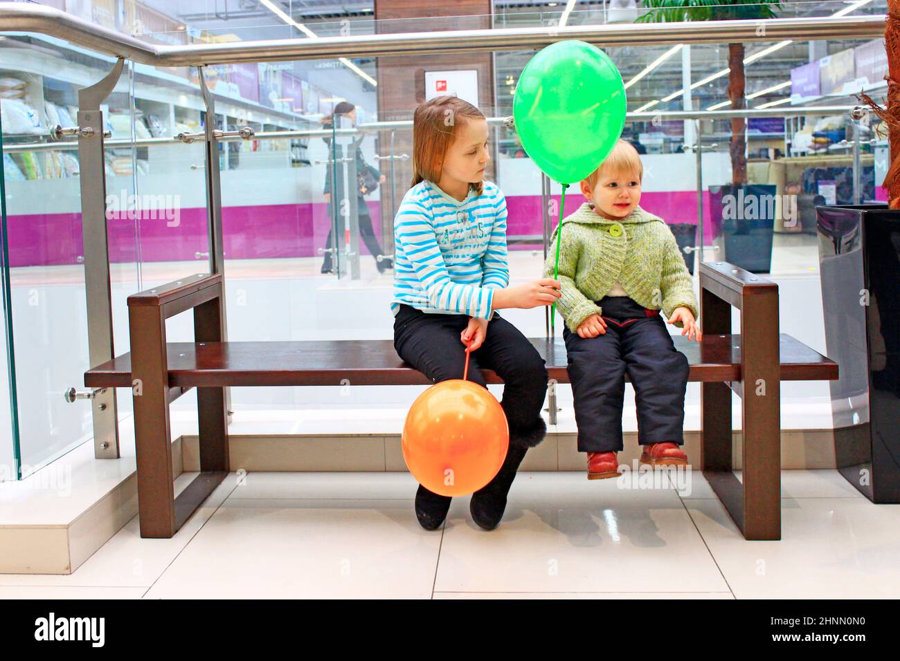 Older sister gives offended younger sister balloon. Childish emotions Stock Photo