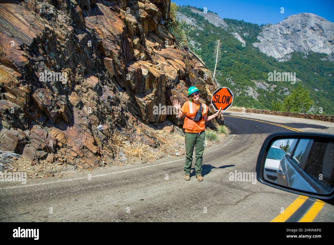 woman regulates the traffic at a road construction site with slow signage. Stock Photo
