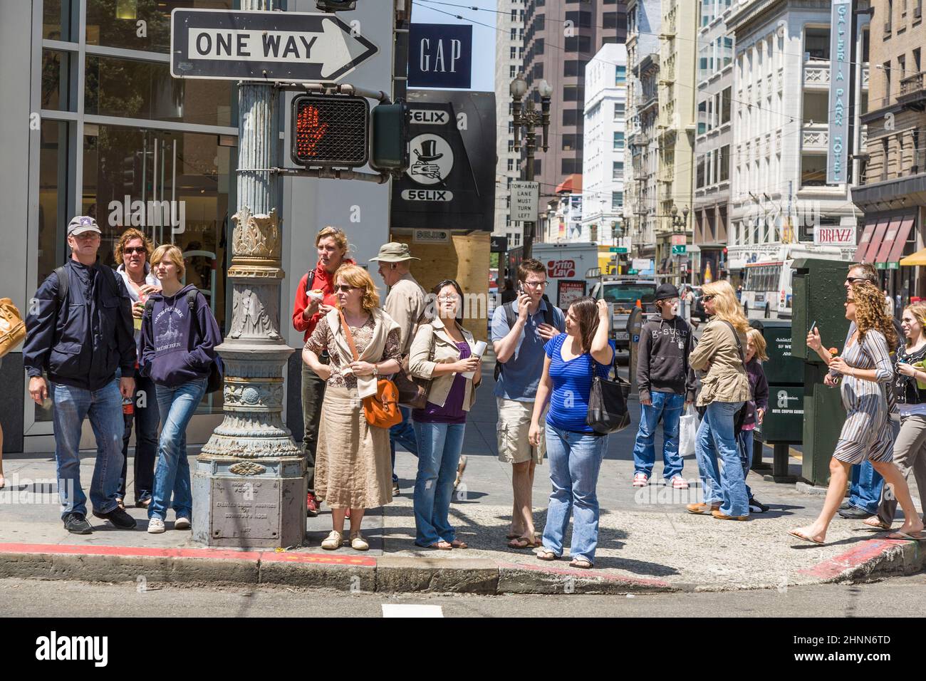 people wait at a pedestrian crossing for green light to cross the street in San Francisco Stock Photo