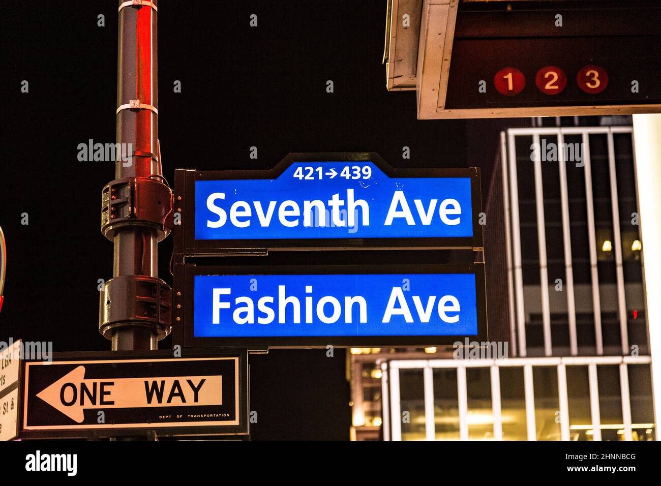 street sigh seventh ave and Fashion Ave in neon light by night in New York Stock Photo