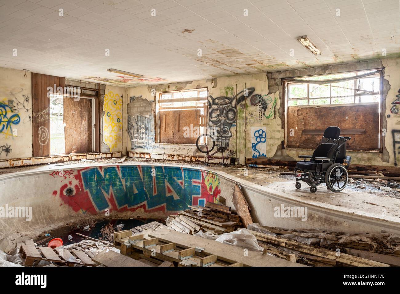 An old and abandoned indoor swimming pool with graffiti and garbage everywhere. Stock Photo