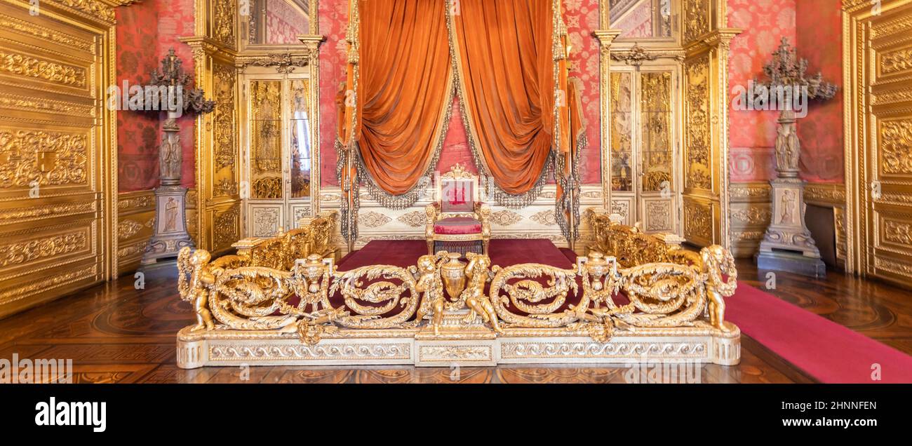 Old throne room interior with chair in luxury palace. Red and gold antique Baroque style. Stock Photo