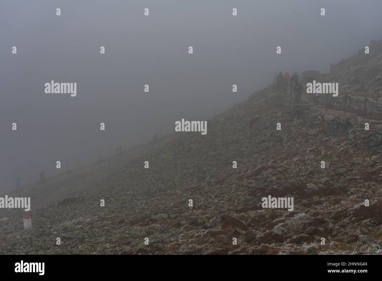 KARPACZ, POLAND - OCTOBER 16, 2021: Tourists climb Poland's popular mountain peak - Sniezka in the Giant Mountains in cloudy weather. Stock Photo