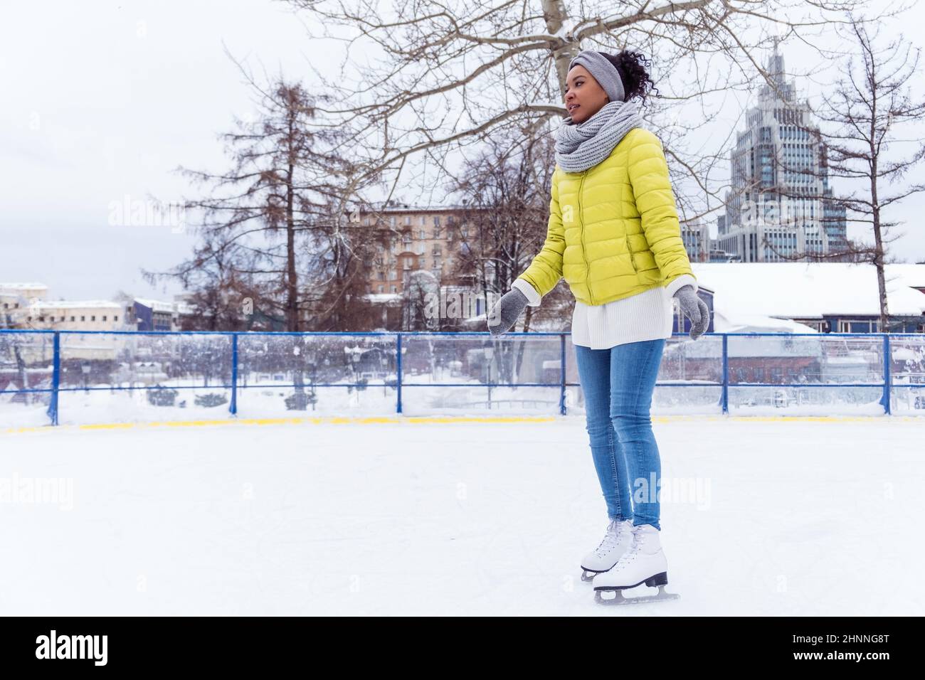 Full lengh portrait of young african american woman skating on ice rink Stock Photo