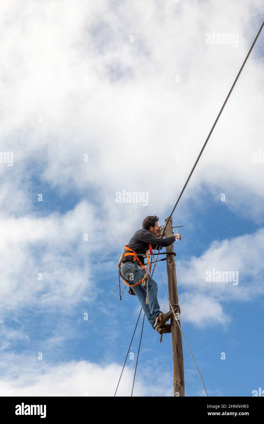 telecommunication worker installs the fiberglass cable for speed internet at an electric pylon Stock Photo