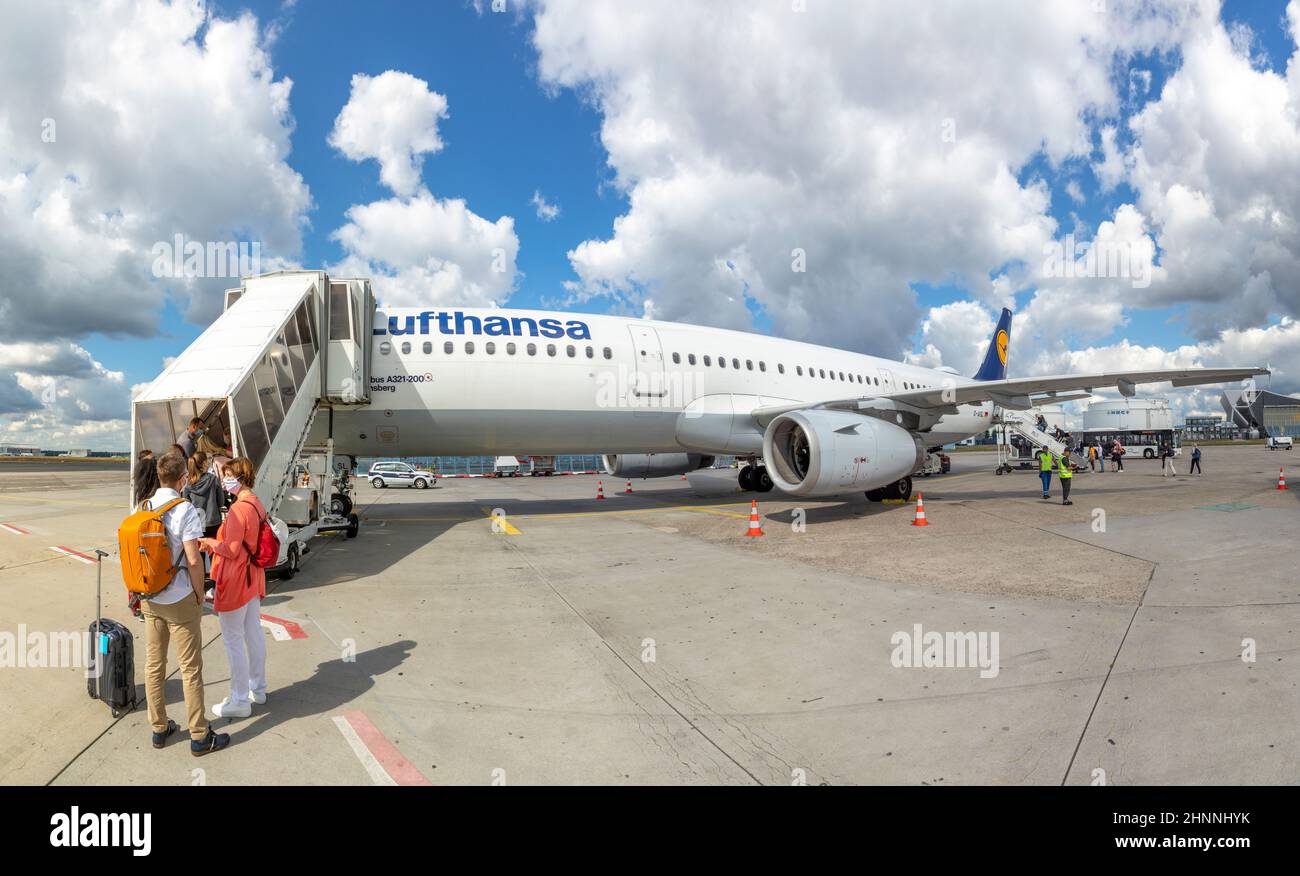 people are boarding the aircraft with distance and face masks at Frankfurt airport. Stock Photo