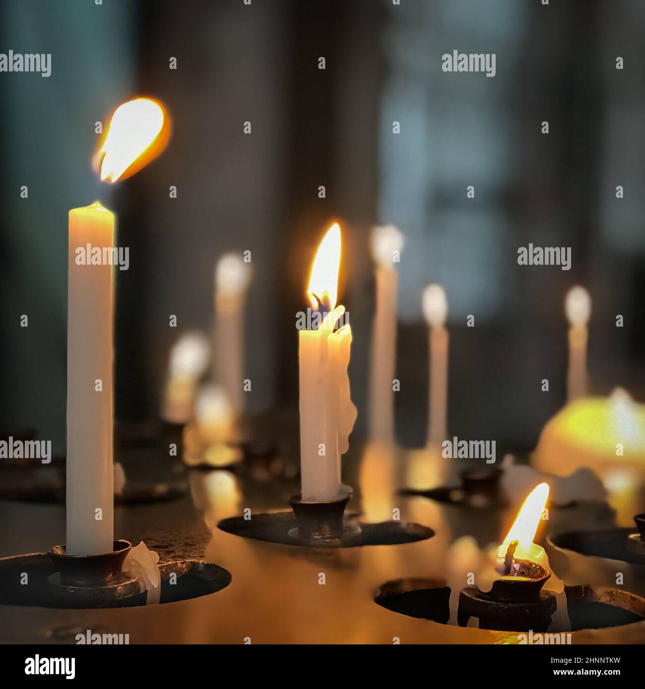 Burning white candles in a church, square Stock Photo Alamy