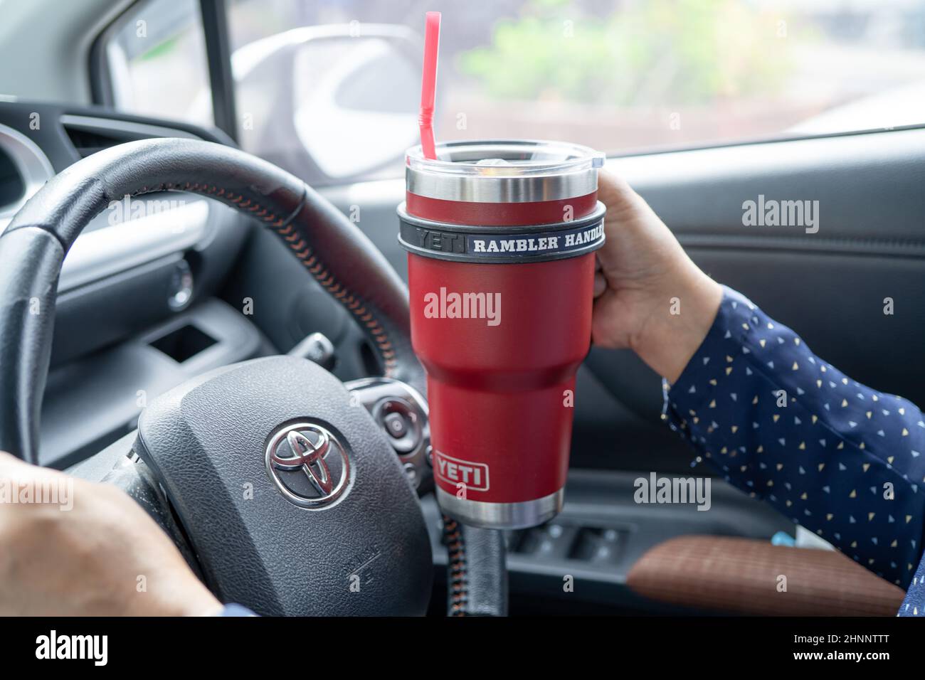 Bangkok, Thailand, July 1, 2021 Asian lady holding ice coffee in Yeti mug cup in toyota car, dangerous and risk an accident. Stock Photo