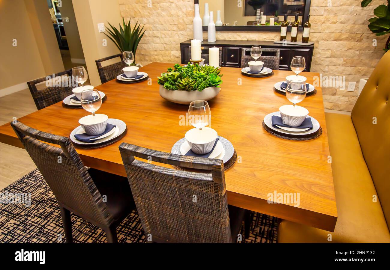Square Wooden Dining Area Table With Eight Place Settings Stock Photo