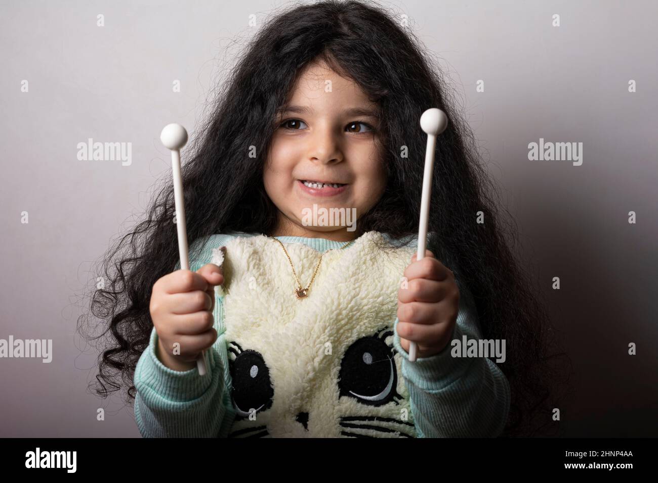 Little girl portrait with xylophone sticks in hands with funny