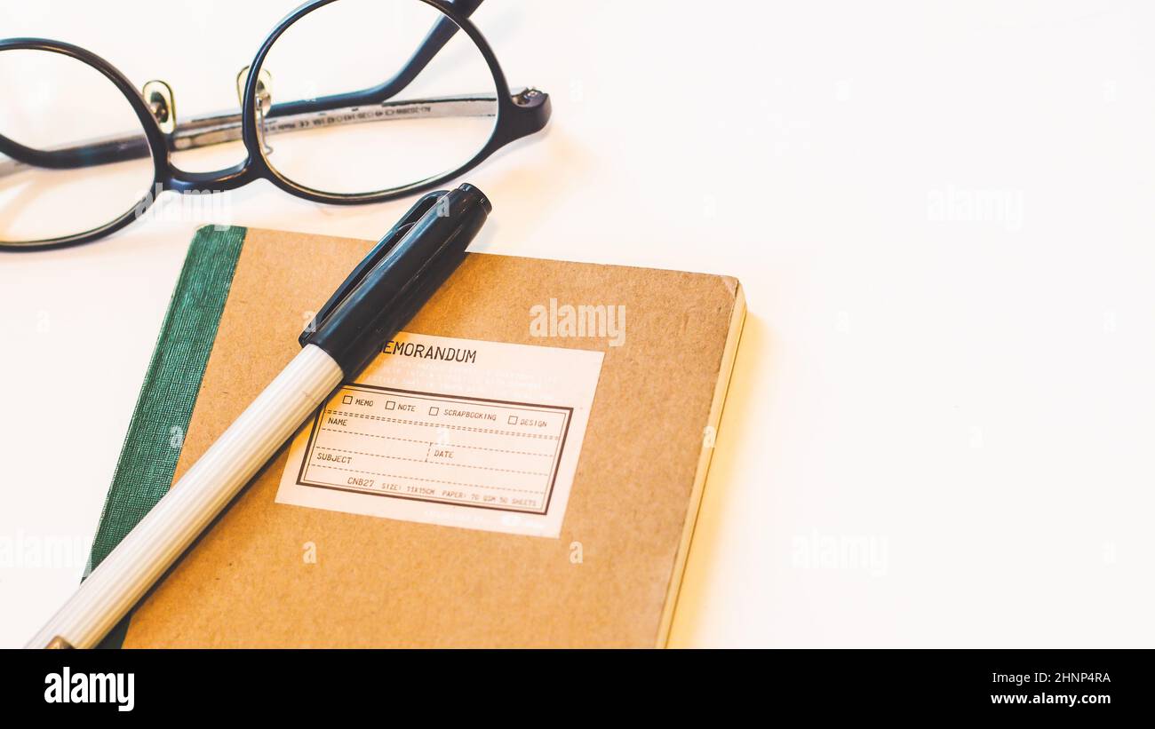 Brown craft paper cover notebook with pen and eyeglasses on desk