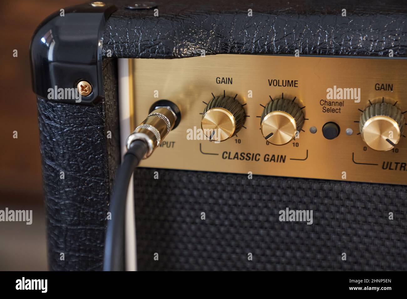 Cable plugged in to a guitar amplifier, adjusting gain and volume