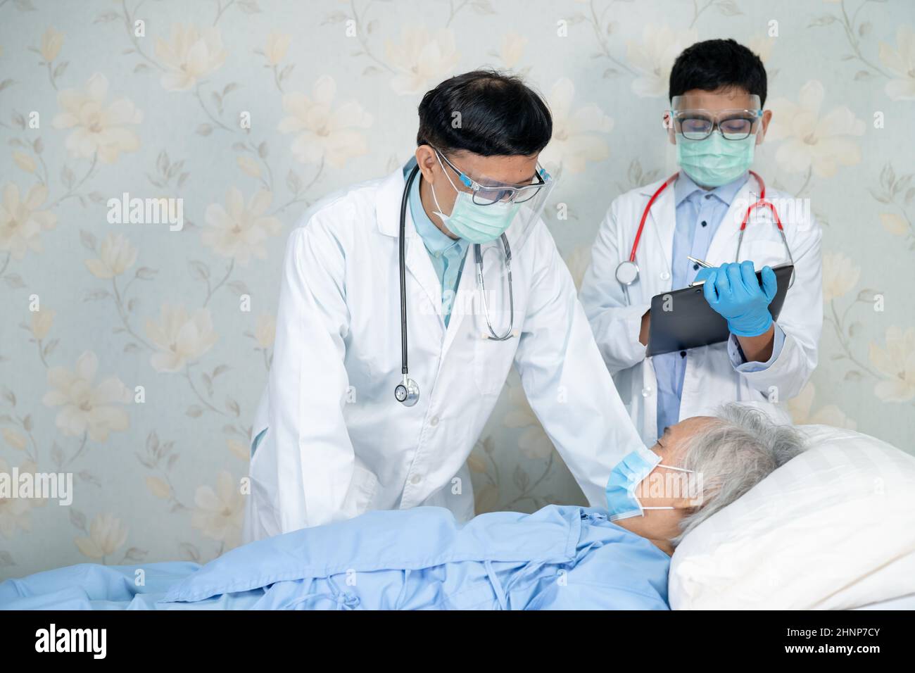 Asian doctor team check old senior lady patient for disease to motivation new normal to treat infection Covid-19 Coronavirus at hospital ward. Stock Photo