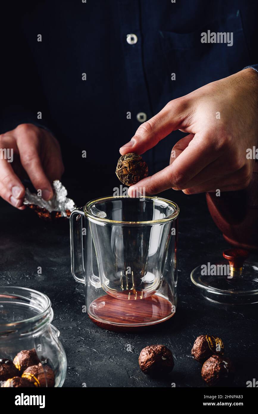 Steeping tea. Putting tea leaves into glass mug Stock Photo