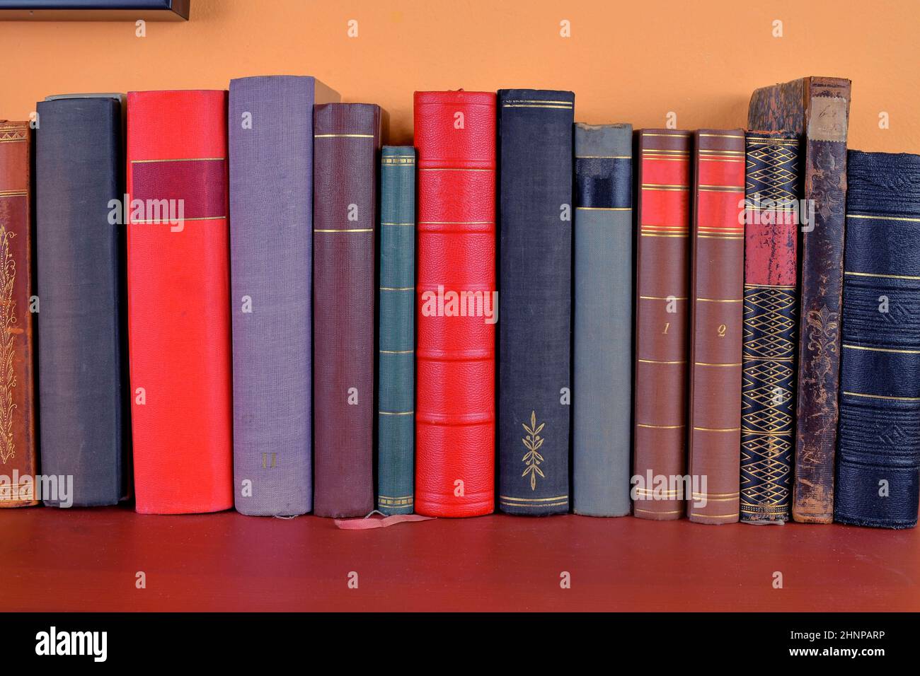 Old antique books background. The ancient books on an orange and claret  background Stock Photo