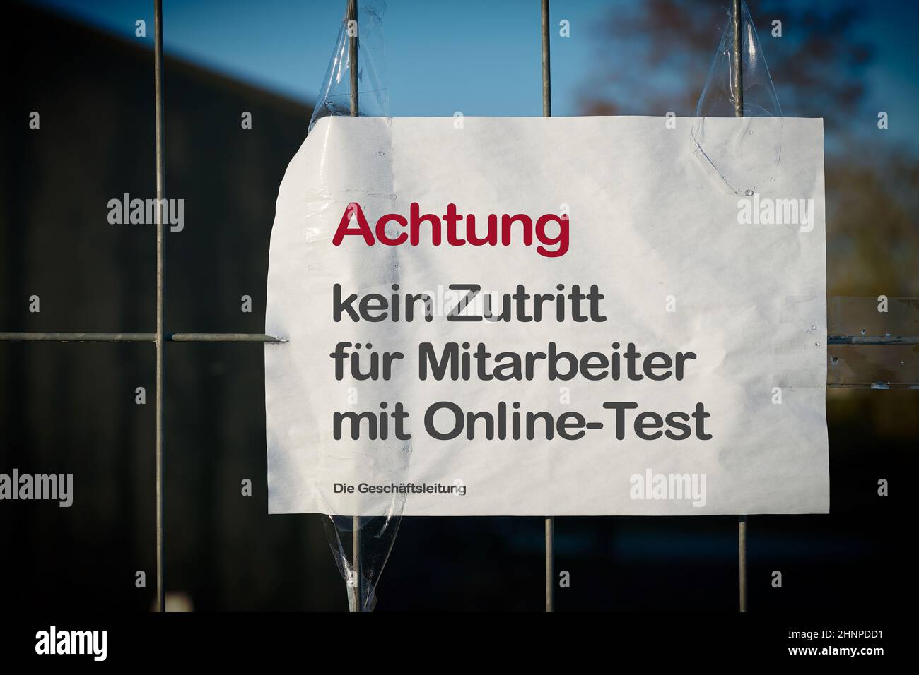 Restricting access at a fence to a company site in Germany during the Corona Pandemic. Translation: Attention, no access for employees with online test Stock Photo