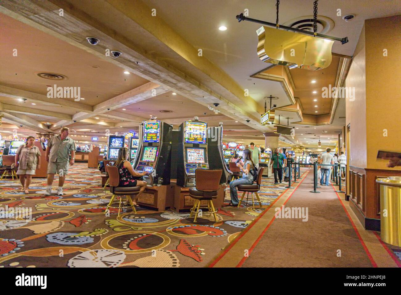 Gamblers sitting inside the casino playing with slot machines Stock Photo