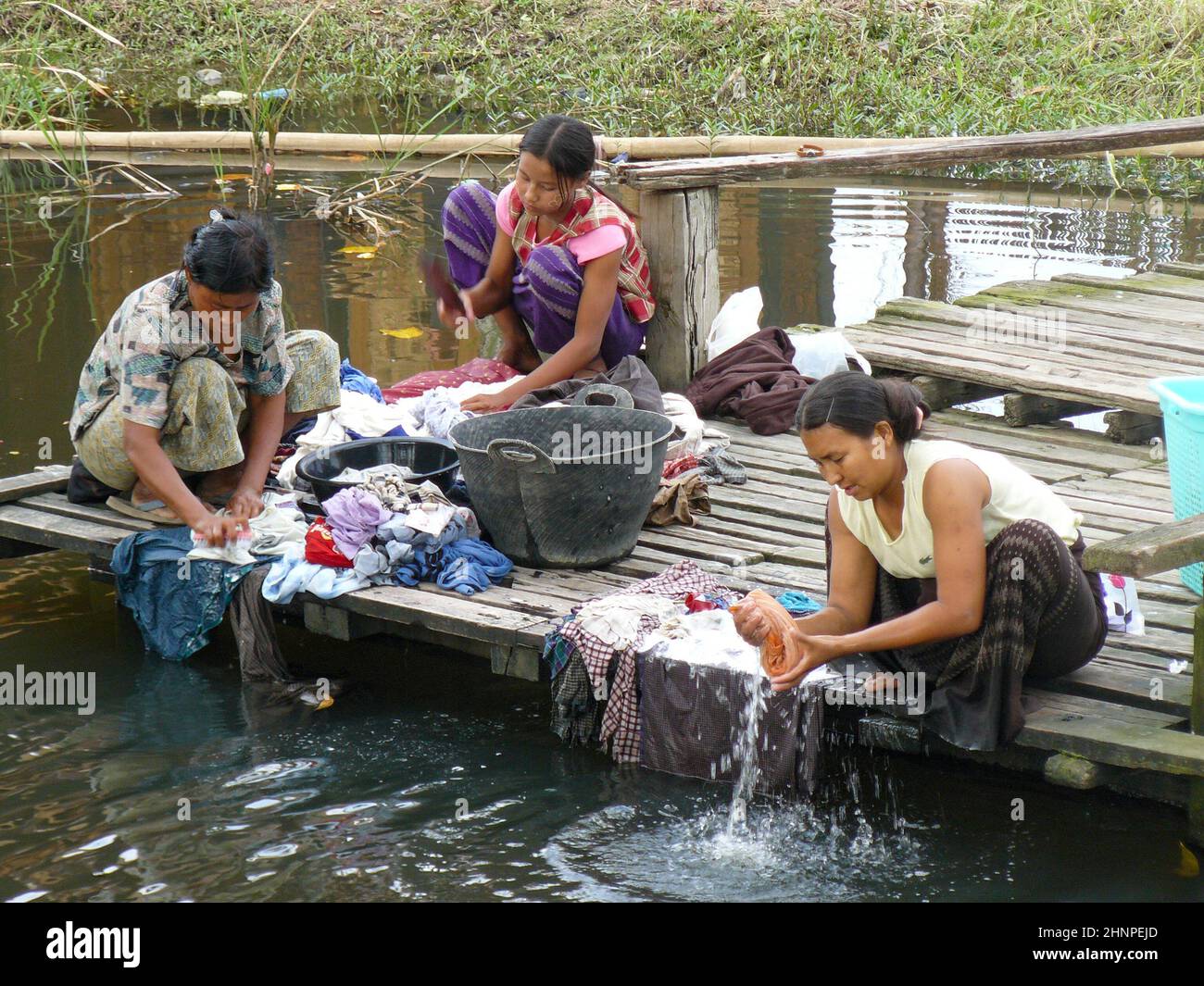 woman in traditional dress washing the clothes in the Inle lake at Intha, Myanmar. Stock Photo