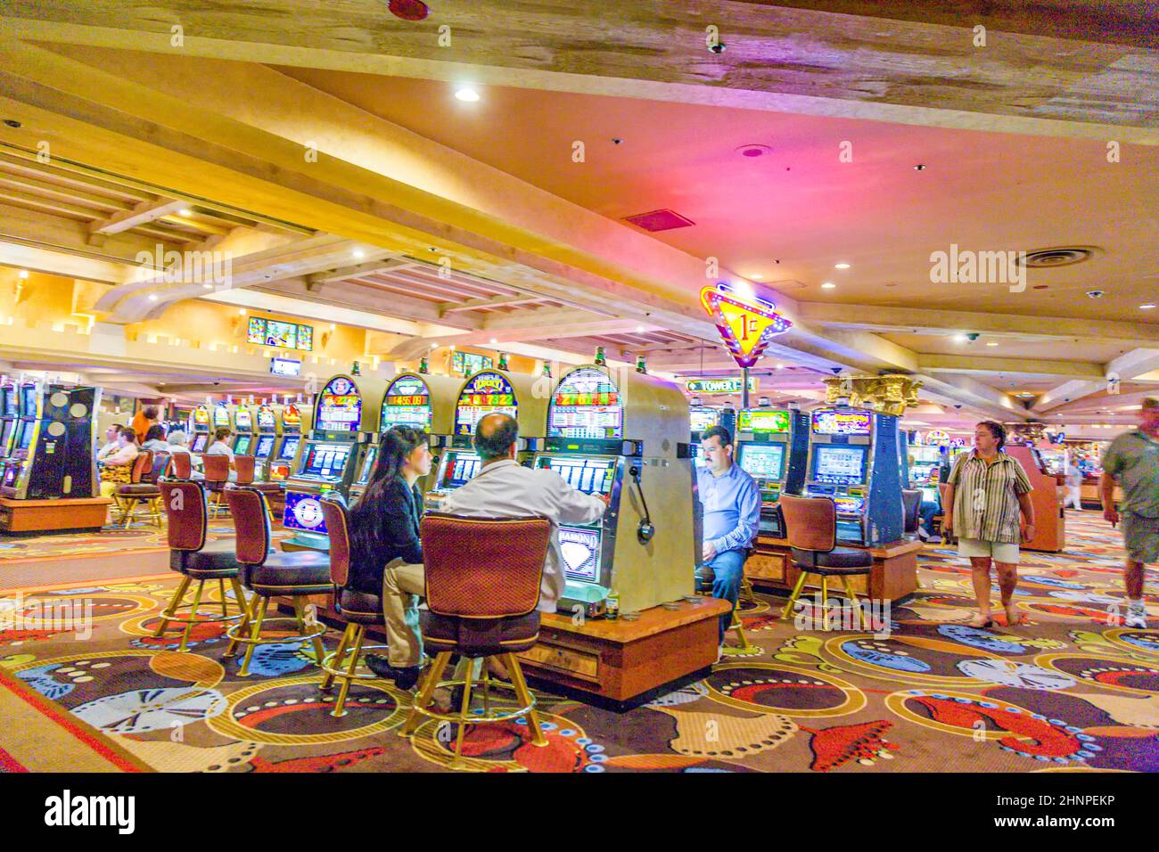 Gamblers sitting inside the casino playing with slot machines Stock Photo