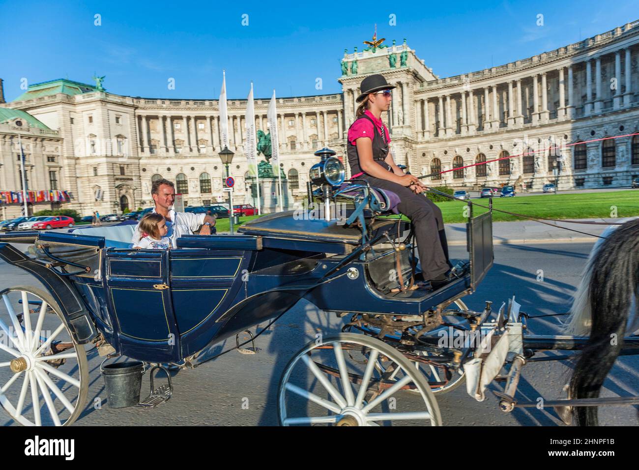 people have a ride in the horsedrawn carriage called fiaker and passing the Vienna Hofburg Stock Photo