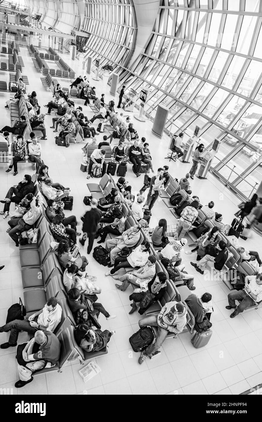 people wait on benches for the departure of their flight at Suvarnabhumi International Airport Stock Photo