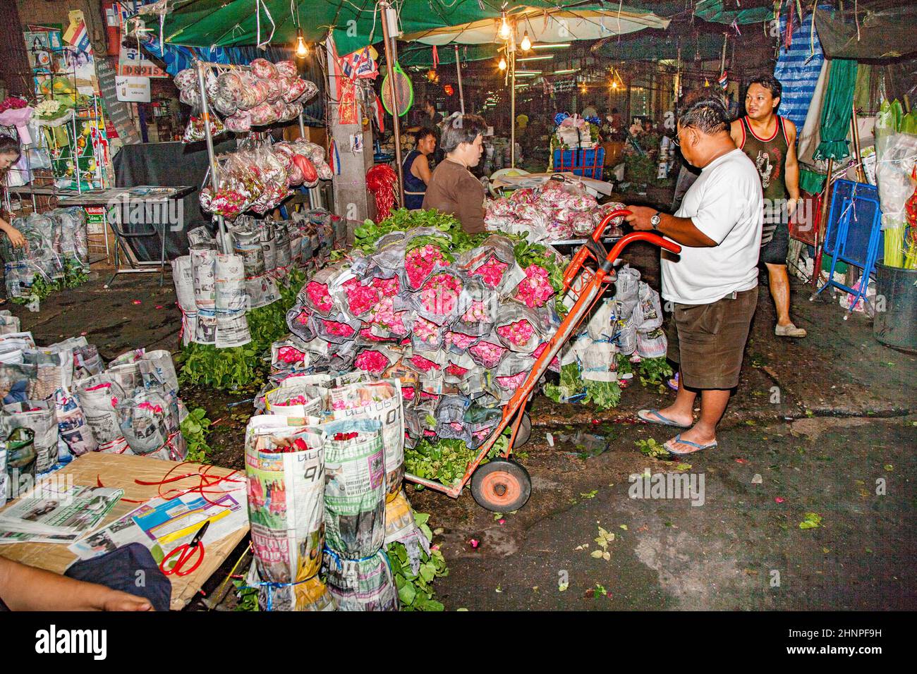 people sell fresh roses at night at the flower market Pak klong Talat in chinatown of Bangkok Stock Photo