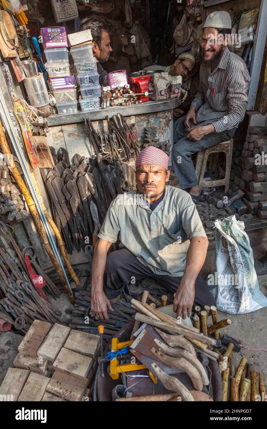 man sits in front of his tooling shop at the street in old Delhi, Chawri Bazaar. Stock Photo