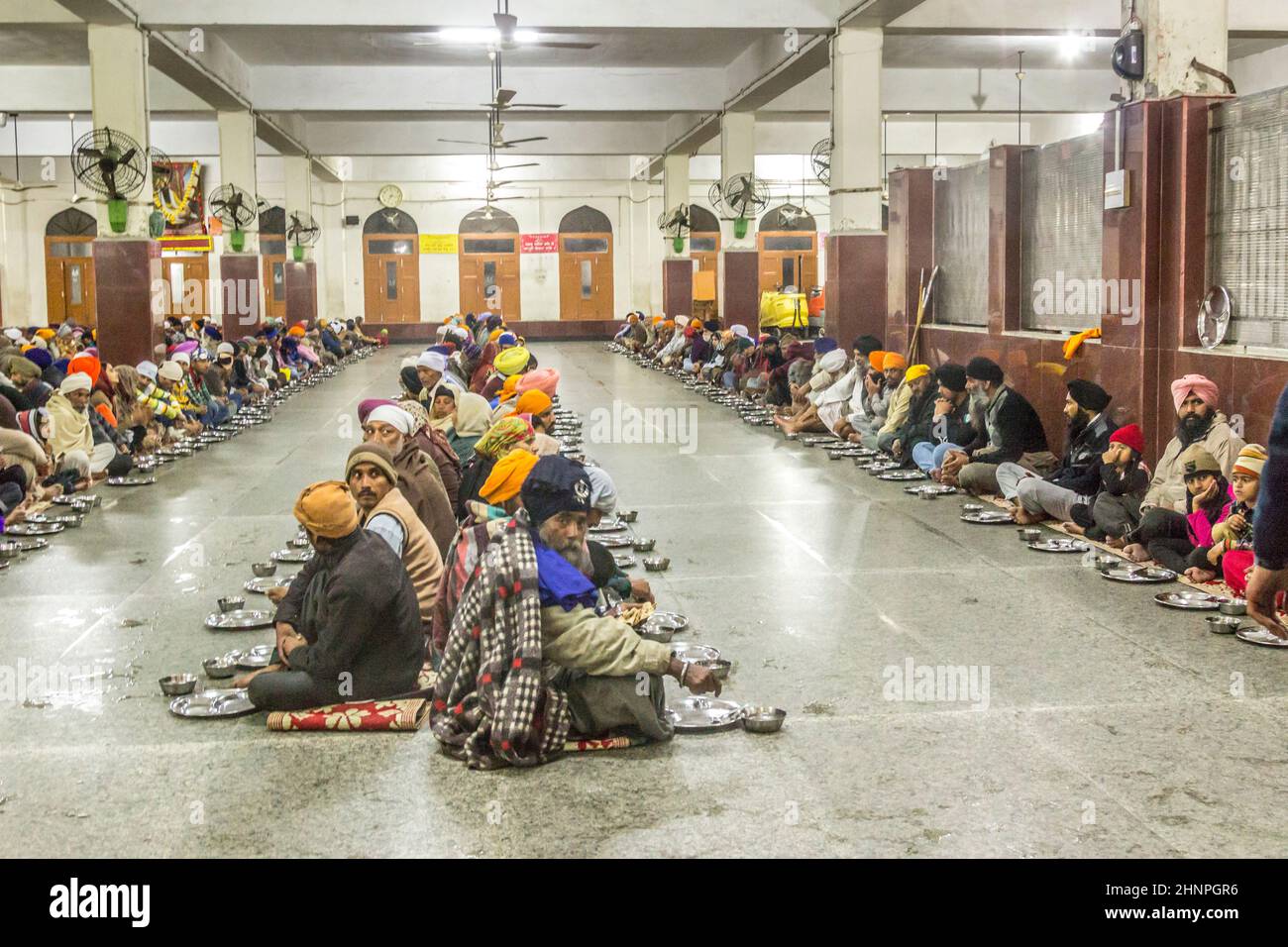 people wait for food in the food  area at the Harimandir Sahib, the Golden temple complex in Amritsar Stock Photo