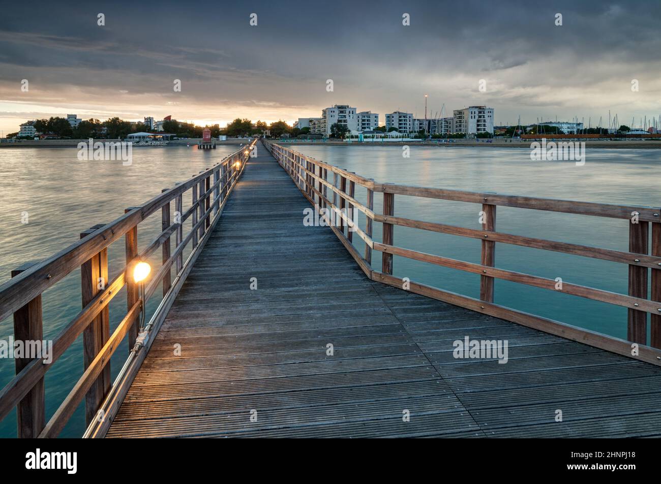 Looking at Lignano Sabbiadoro from wooden pier at sunset Stock Photo