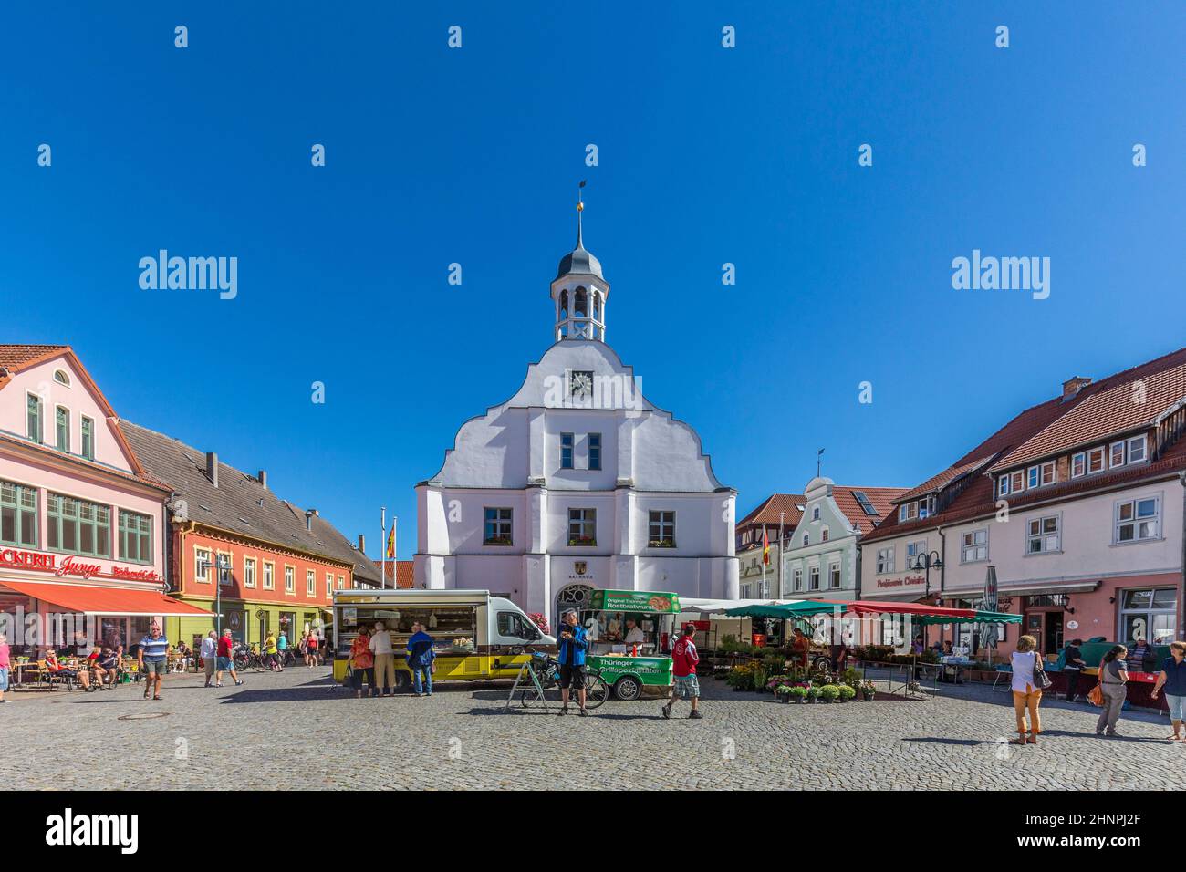 people enjoy gothic St Petri church in Wolgast under blue sky with historic market place Stock Photo