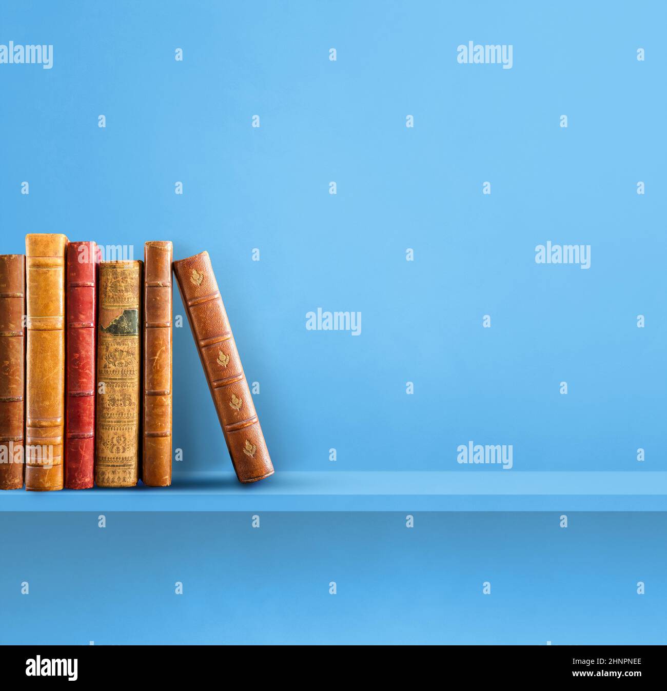 Row of old books on blue shelf. Square background Stock Photo
