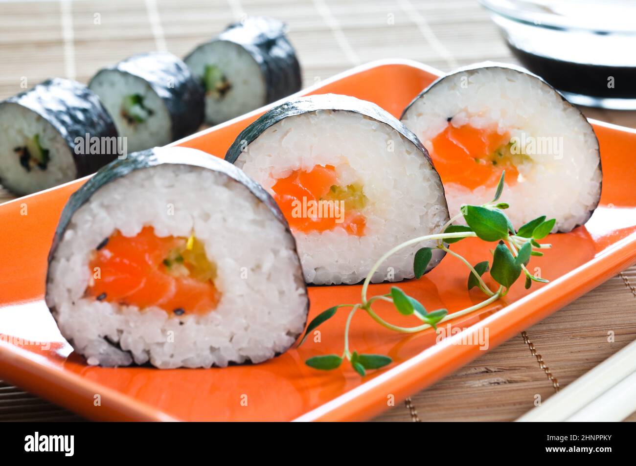 Selection of Japanese sushi arranged with thyme on red plate Stock