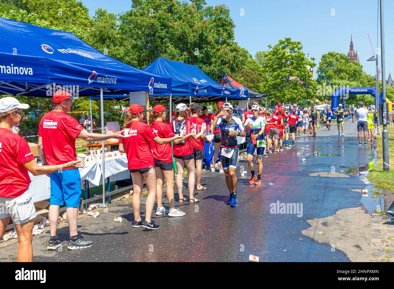 athletes drink mineral water or get a shower while running at the frankfurt ironman 2019. Because of the heat the caterin stations are enlarged Stock Photo