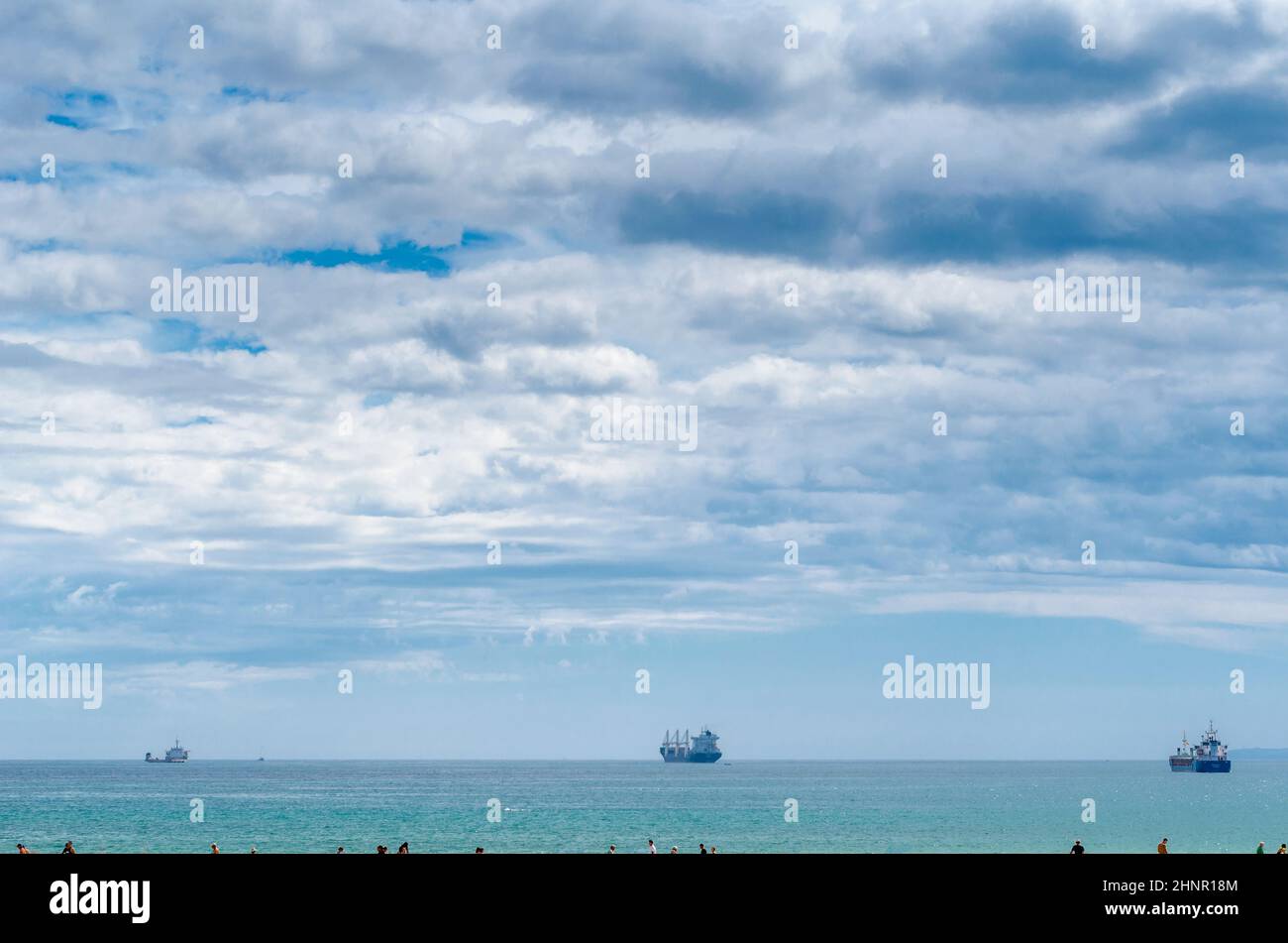 SANTANDER, SPAIN - JULY 3, 2021: Seascape in Santander, with people walking on the beach and boats in the background Stock Photo