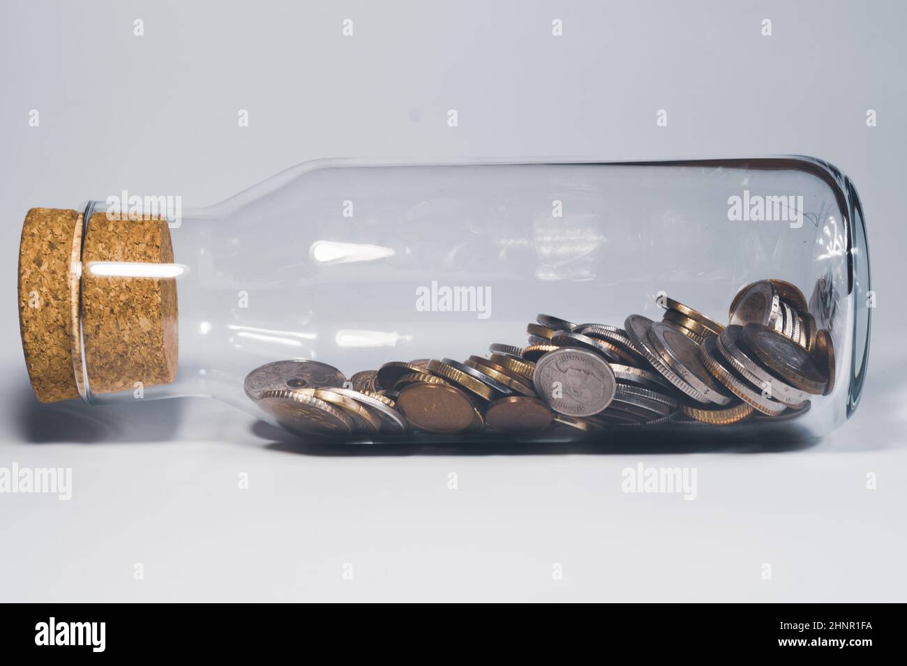 Glass jar with cork stopper and filled with international coins from various countries