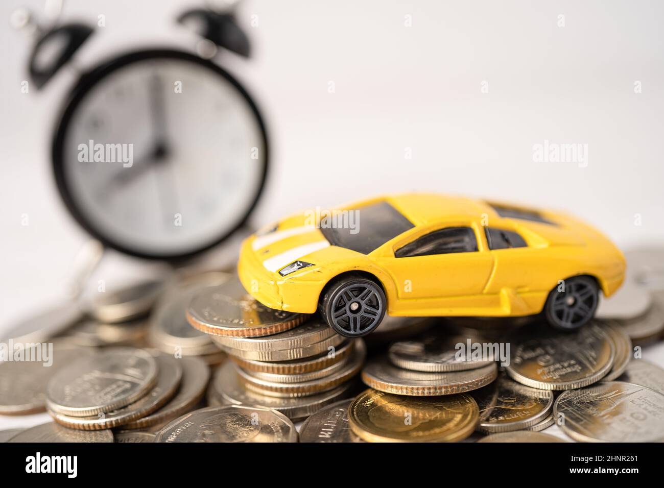 Car and alarm clock on coins, Car loan, Finance, saving money, insurance and leasing time concepts. Stock Photo