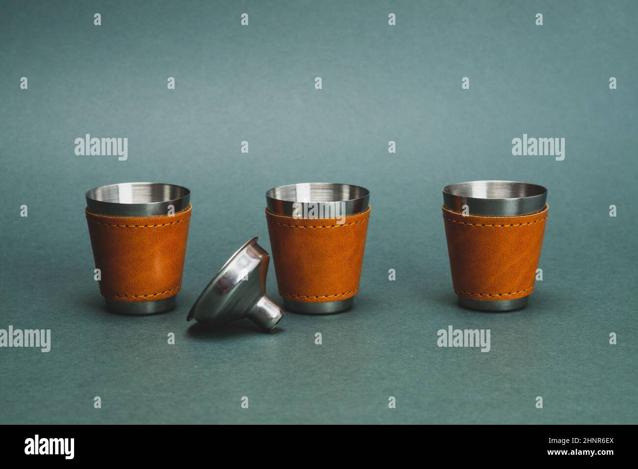 Metallic shot glasses in a row. steel funnel. travel shot glass for alcohol with leather casing