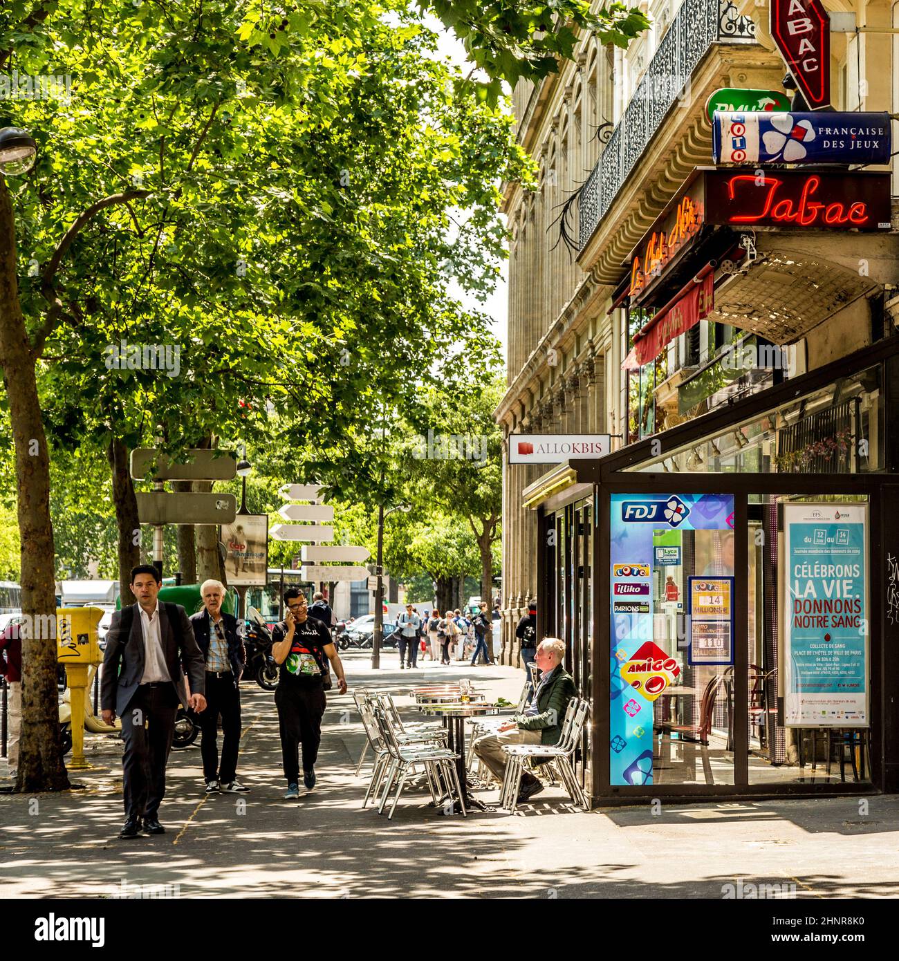 man sitting in a typical bar with tabac shop and winter gardenn at the walk way Stock Photo