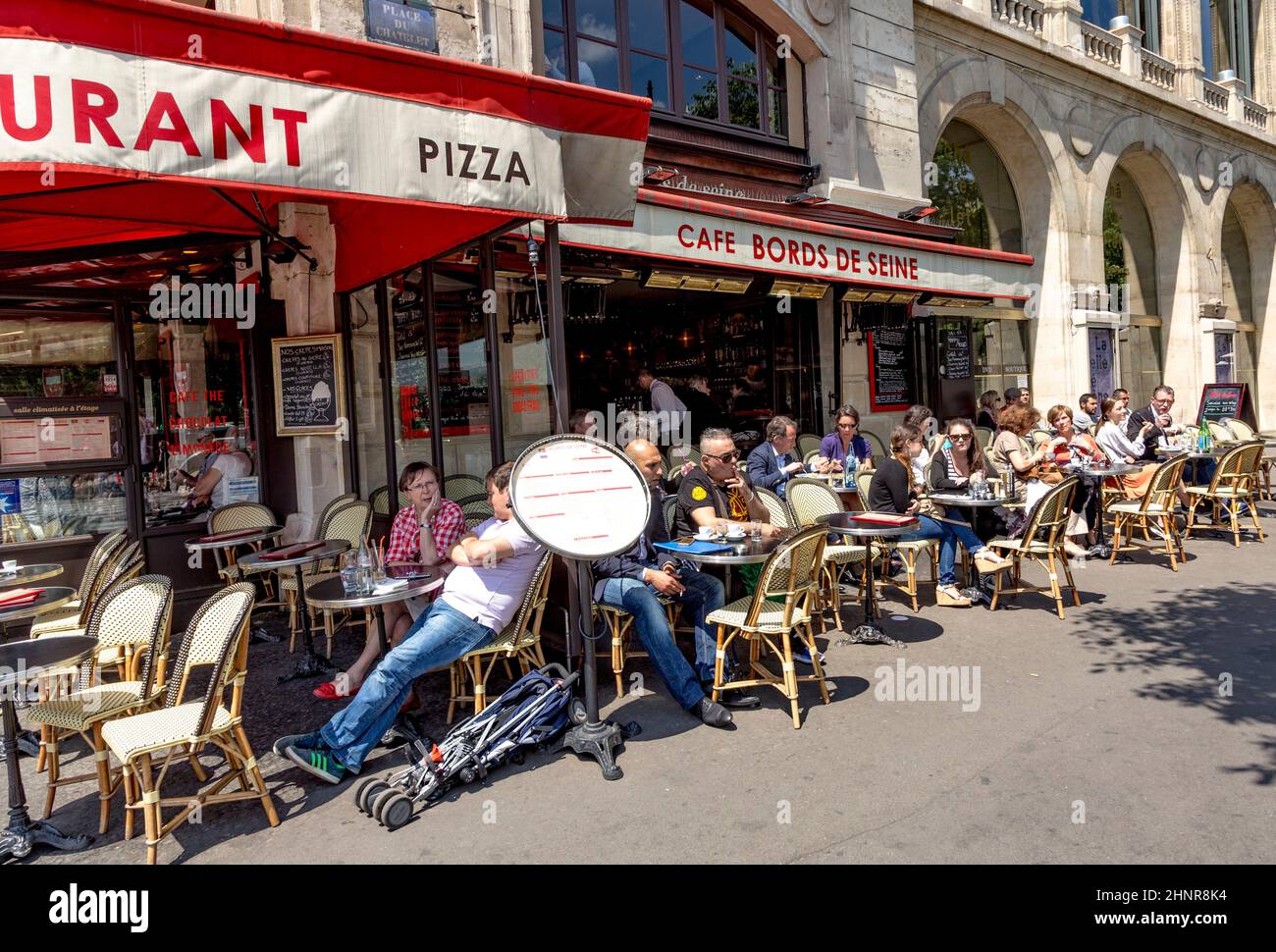 people enjoy sitting in the sun in the cafe Stock Photo